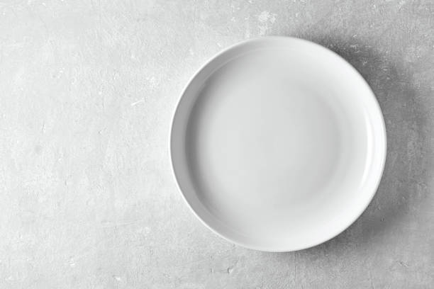 istock Empty white plate on a gray stone background. Template for displaying food on menu 1695879461