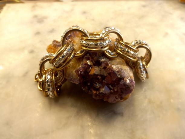 istock Gold and Silver Chain Resting on Amethyst Gemstone Rock 1695889109