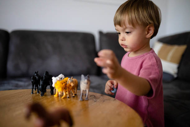 istock Cute boy is playing with toy animals 1695966250