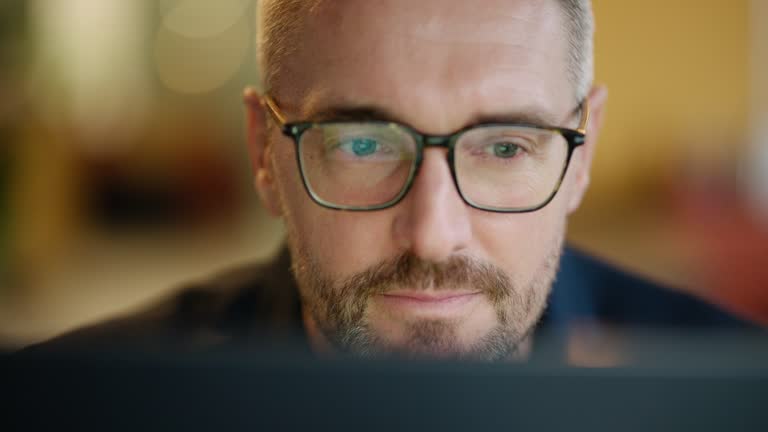 Geschäftsmann, Brille und Lesen am Computer in der Programmier-, Software- oder Informationstechnologielösung. Professionelle Programmierer oder Manager beginnen mit der Arbeit am Laptop, um IT-Probleme zu lösen oder Ergebnisse zu erzielen