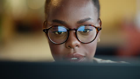 Leitura, rosto e mulher no laptop com óculos à noite para trabalho na internet, artigo e notícias. Closeup de pessoa africana profissional no computador para pesquisa de jornalistas, resultados de trabalho on-line ou planejamento