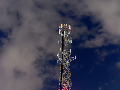5G  tower against a starry partially overcast night sky.