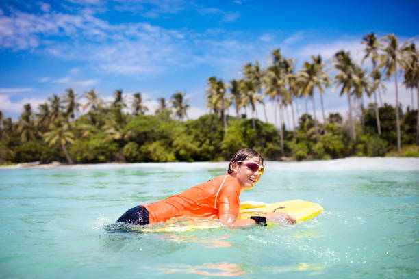 istock Child surfing on tropical beach. Surfer in ocean. 1696082747