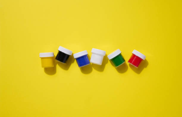 istock Plastic jars with multi-colored gouache on a yellow background, copy space 1696085429