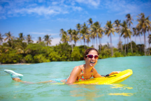 istock Young woman with surf board on tropical beach 1696089962