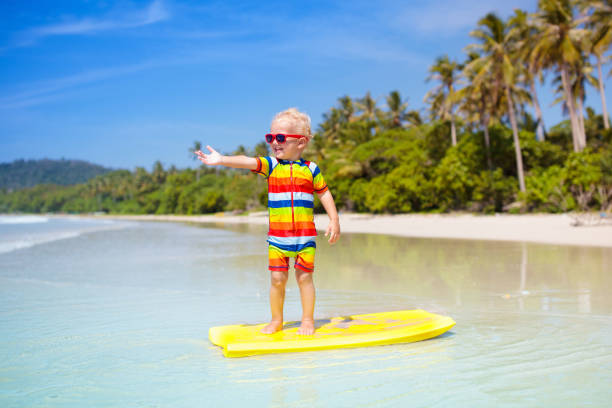 istock Child surfing on tropical beach. Surfer in ocean. 1696098547