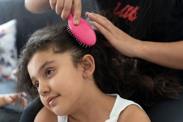 A girl being combed by her mother. A girl being combed by her mother. Mother fixing her daughter's hair. Mini Hairbrush or Comb stock pictures, royalty-free photos & images