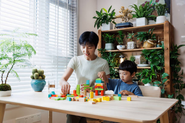 istock young mom is playing building blocks with her son at livingroom 1696163286
