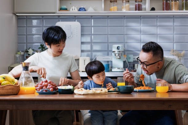 幸せな両親と息子は家で一緒に昼食をとります - 健康　子ども ストックフォトと画像