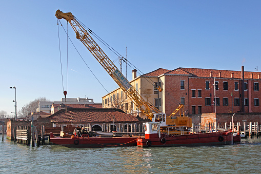 Venice, Italy - December 19, 2012: Construction Crane at Barge Vessel at Water Canal in City Centre Winter Day.