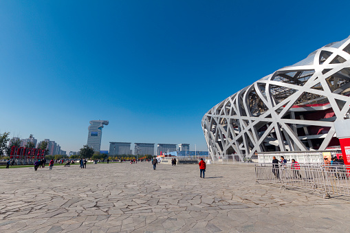 Beijing, China, October 31sth, 2015. View of the Bird’s Nest Olympic stadium and modern office buildings in the background with visitors.
