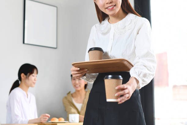 young asian female clerk passing drinks working at a restaurant - soda jerk imagens e fotografias de stock