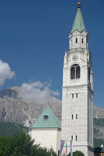 The bell tower of the Parish Church of Cortina d'Ampezzo, with the Dolomites in the background