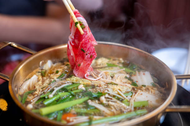 istock Chopstick holding sliced meat. hot pot with thick soup. 1696430542