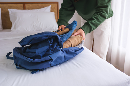 Closeup image of a woman packing clothes in backpack for travel at home