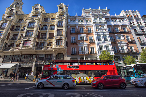 View of Gran Via street on a sunny afternoon, Madrid, Spain.  A tour bus in the street with beautiful buildings.