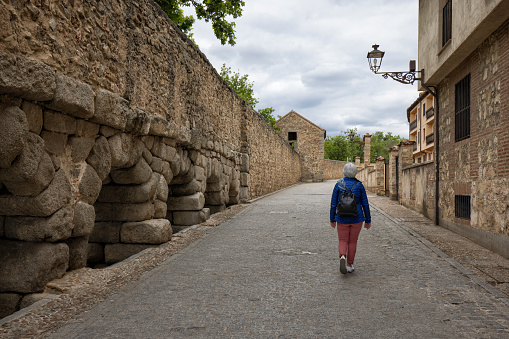 Street view of the Roman Aqueduct, Segovia, Spain. Senior woman walking down the street.