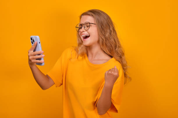 istock Young overjoyed Caucasian woman makes video call on phone stands in studio 1696467287