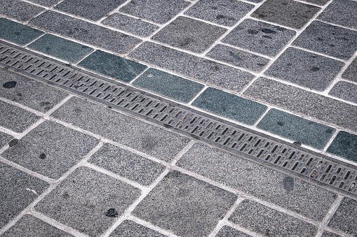 metal rainwater grate. concrete pavement walkway.