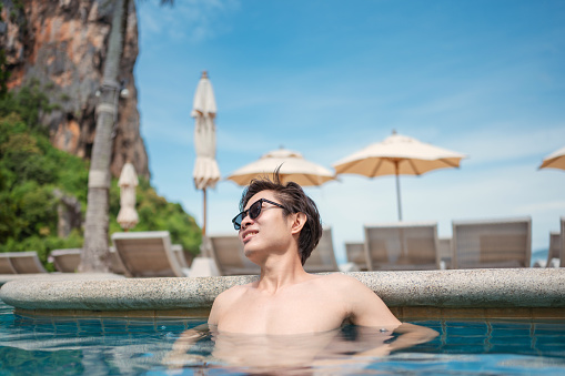 Asian men sunbathing at beach side pool  relaxing in the water Portrait tropical paradise Beachfront Swimming Pool