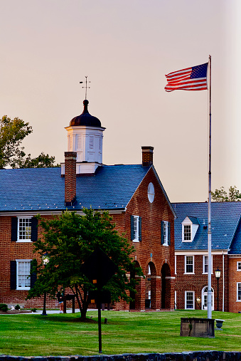 Fairfax, Virginia, USA - September 22, 2023: An American flag flies briskly in the wind at dusk at the Historic Fairfax County Courthouse in Old Town Fairfax.