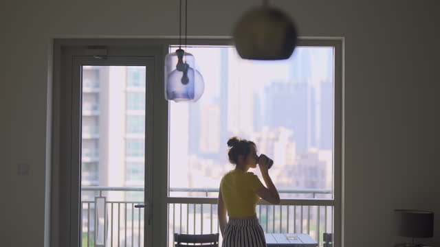 Woman looking at cityscape and having her morning cup of coffee