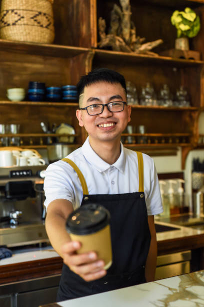 istock Vietnamese smiling waiter holding paper cups with coffee in a cafe 1696573356