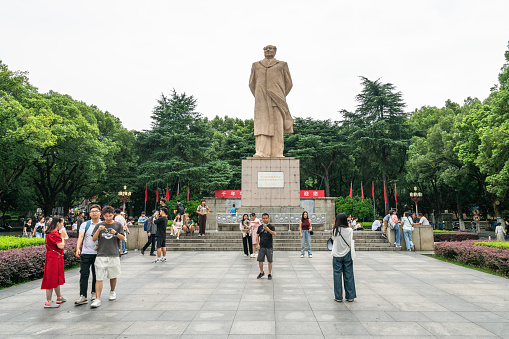 Changsha, China - August 29, 2023 - Tourists take photographs of a large statue of Mao Zedong at Hunan University. Mao was a student in Changsha and began his political career there.
