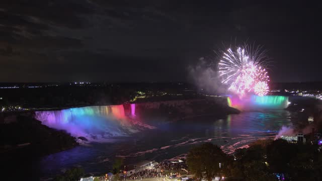 Elevated view of fireworks above multi colored illuminated American and Horseshoe falls