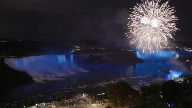 Elevated view of fireworks above pink colored illuminated Niagara falls