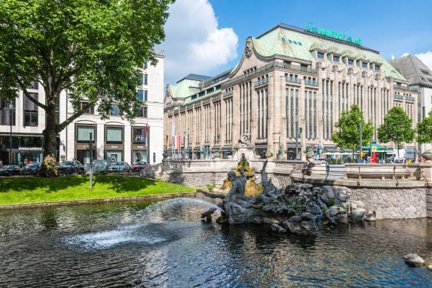 Street life and architecture in Dusseldorf, North Rhine-Westphalia, Germany Dusseldorf, Germany - June 2, 2022: Outdoor view of Tritonenbrunnen fountain and beautiful waterside area at Konigsallee, famous shopping street, and background of the Steigenberger Parkhotel. triton greek god stock pictures, royalty-free photos & images