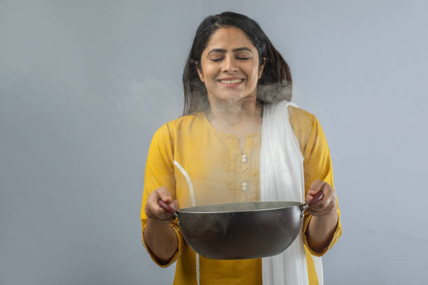 Woman holding cooking pan while standing over white background
