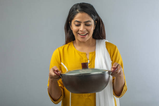 istock Woman holding cooking pan while standing over white background 1696633427