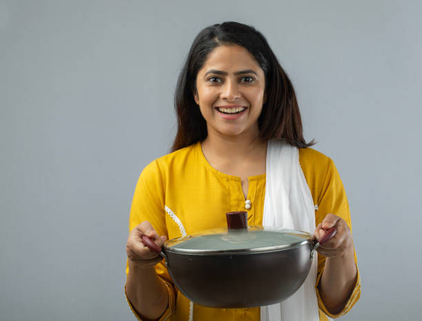 istock Woman holding cooking pan while standing over white background 1696633458