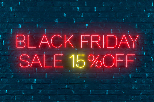Black Friday 15% off Sale with Neon Light on Black Brick Wall. Digitally generated image.