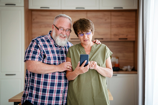 Mature couple using a smartphone while at home
