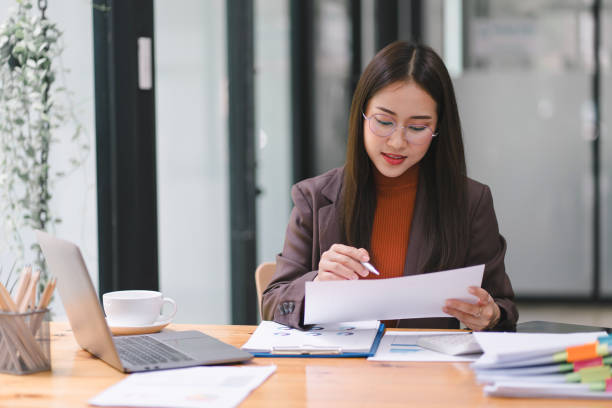 istock Asian businesswoman or accountant using a calculator, graphs, and charts to analyze market data, balance sheets, accounts, and net profits. 1696648236