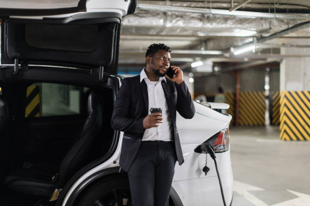 istock E-car driver with cup receiving phone call during recharge 1696649964