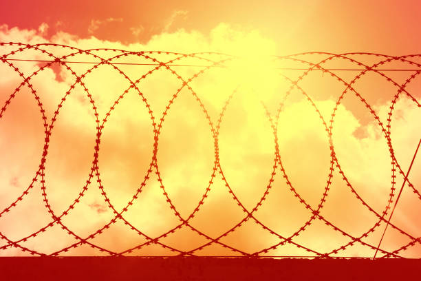 the red sky from the explosion behind the barbed wire. The war in Ukraine