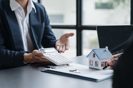 An entrepreneur, business owner, accountant, and young Asian real estate agent who uses home-buying budget calculator calculate the financial risks for clients before signing a deal.