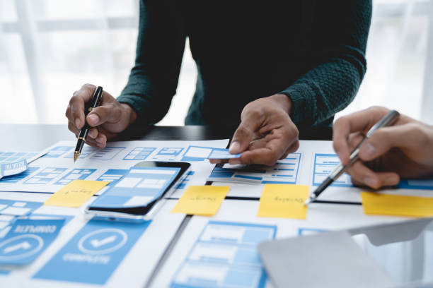 istock ux developers, UI designers Asian group data researchers brainstorm on tabletop mobile app interface wireframe design client summary color codes modern office Creative Digital Development Agency. 1696691961