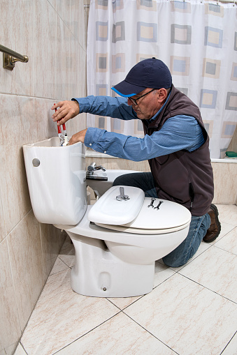 Professional plumber repairing a toilet cistern