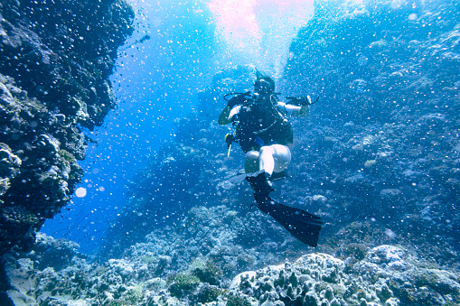 Lady diver in the Red Sea, Yanbu, Saudi Arabia. In the background a gorge in the reefs