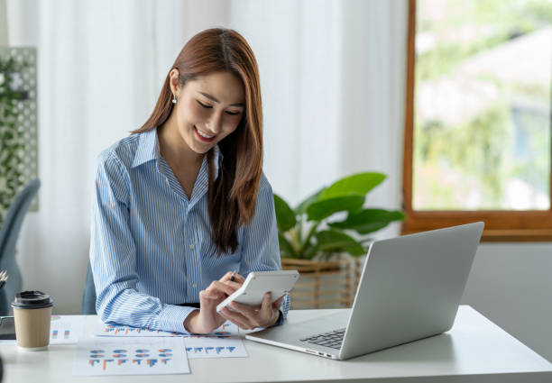 femme d’affaires asiatique travaillant au bureau pressant calculateur de revenu résultats financiers pour l’enregistrement. - women prosperity calculator computer photos et images de collection