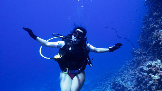 Lady diver in the Red Sea, Yanbu, Saudi Arabia. In the background a gorge in the reefs