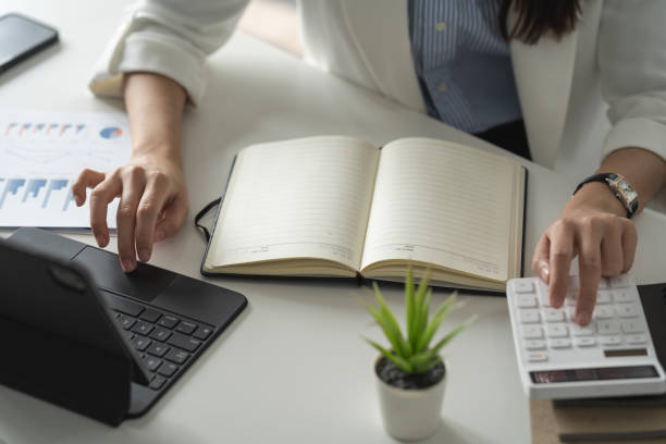 asiatische geschäftsfrau, die im büro arbeitet einkommensrechner finanzergebnisse für die aufzeichnung. - women prosperity calculator computer stock-fotos und bilder