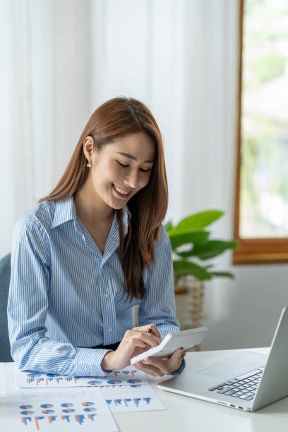 femme d’affaires asiatique travaillant au bureau pressant calculateur de revenu résultats financiers pour l’enregistrement. - women prosperity calculator computer photos et images de collection