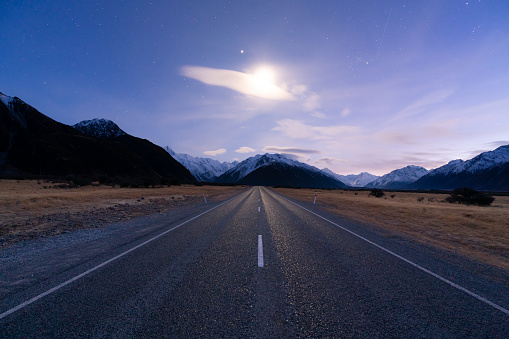 With dawn approaching to the east, stars twinkle above the road to Mt Cook on New Zealand's South Island.