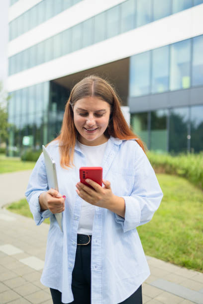 istock Happy business woman holding a digital laptop reading a text message on her phone while commuting to work in the city 1696726007