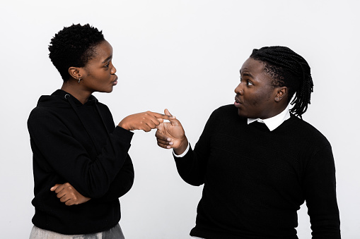 African amercan couple standing over white background in studio isolated arguing blaming each other relation troubles or seperation serious man and woman pointing at each other quarrel time.